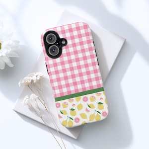 May include: A phone case with a pink and white gingham pattern on the top half and a green stripe separating it from the bottom half. The bottom half features a lemon and pink grapefruit design.