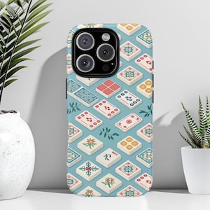 May include: A phone case with a repeating pattern of colorful Mahjong tiles on a light blue background. The tiles feature various designs in red, yellow, green, and white. The case has a black camera module.