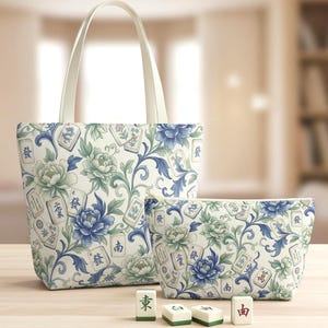 Könnte beinhalten: Eine Tragetasche und eine Kosmetiktasche mit einem Blumen- und Mahjong-Fliesenmuster in Blau, Grün und Weiß. Die Tragetasche hat cremefarbene Griffe. Vier Mahjong-Steine ​​liegen vor den Taschen.