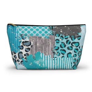 Op de afbeelding: Een make-up tasje met ritssluiting en patchwork design. De tas heeft een mix van patronen, waaronder turquoise stippen, luipaardprint en verticale strepen. Het kleurenpalet omvat turquoise, grijs en wit, met een gouden rits.