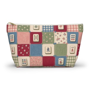 May include: A zippered pouch featuring a patchwork design of squares with floral patterns, gingham checks, and various mahjong tiles. The tiles display Chinese characters and circular motifs in red, blue, and green colors. The pouch has a gold-tone zipper.