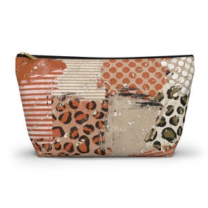 Op de afbeelding: Een rechthoekige make-uptas met een patchwork-ontwerp. De tas heeft verschillende patronen, waaronder strepen, stippen en luipaardprint, in tinten oranje, bruin en beige. Hij heeft een zwarte ritssluiting en een goudkleurige ritstrekker.