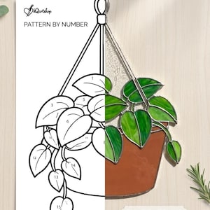 May include: Stained glass pattern and sample of a hanging plant in a brown pot. The image is split, with the left side a black and white pattern by number, and the right side a completed stained glass design with green leaves.
