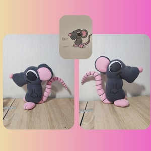 May include: A plush rat toy with a dark gray body, pink ears, feet, and tail. The rat has large, round eyes and a small pink nose. A drawing of a rat with the word "RAT" is in the background.