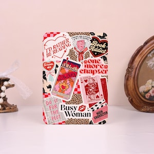 May include: A rectangular sticker sheet with various colorful designs and text. The sheet includes stickers with phrases like "I'd Rather Be Reading," "Book Addict," and "Busy Woman." Other stickers feature a matchbox, playing cards, and a bouquet of flowers.