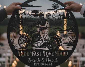 May include: A circular black metal wall sign featuring a cutout illustration of a couple on a motorcycle against a mountain landscape. The text reads RIDE FAST LOVE HARD, Sarah & David, EST. 10.26.24 in a mix of serif and script fonts.