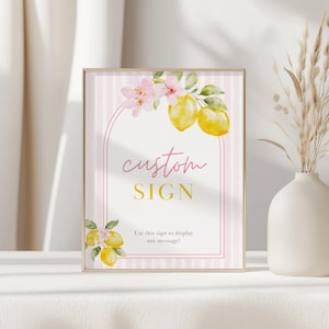 Puede incluir: Un letrero enmarcado con un borde dorado, con un fondo a rayas rosas y blancas. El letrero está decorado con limones de acuarela, flores rosas y las palabras "custom SIGN" en rosa y dorado. El texto en la parte inferior dice "¡Usa este letrero para mostrar cualquier mensaje!"