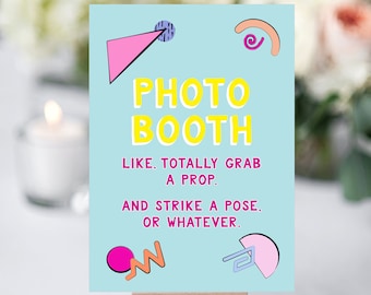 May include: A light blue sign with geometric shapes in pink, orange, and purple. The sign says "PHOTO BOOTH" in yellow letters and "LIKE, TOTALLY GRAB A PROP. AND STRIKE A POSE. OR WHATEVER." in black letters.