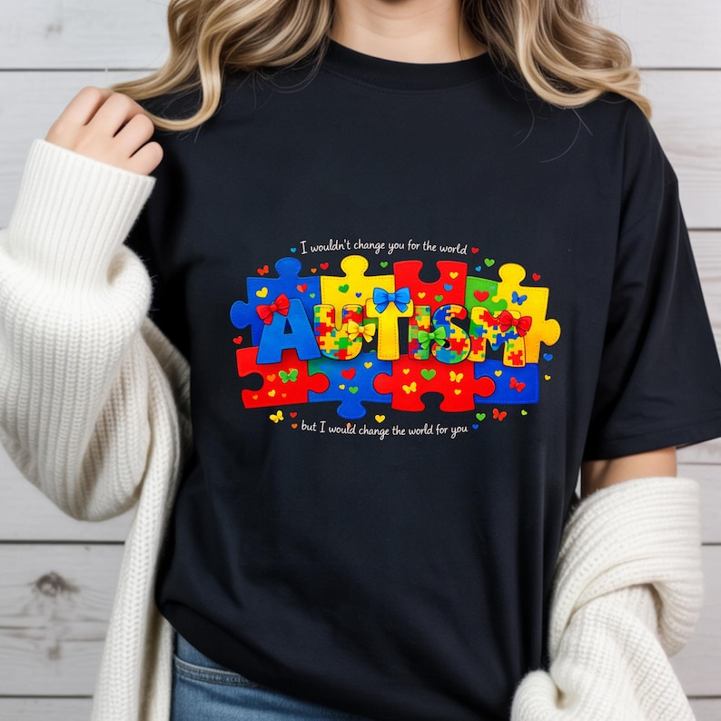 May include: Black t-shirt with a colorful puzzle piece design spelling "AUTISM". The design includes the text "I wouldn't change you for the world, but I would change the world for you."