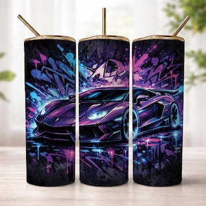 May include: A cylindrical tumbler with a lid and straw featuring a purple sports car graphic set against a dark background with vibrant blue and pink graffiti-style paint splatters and abstract shapes that wrap around the entire surface.