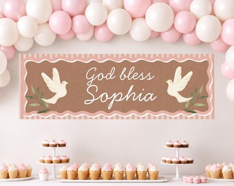May include: A rectangular banner with a brown center and pink striped border featuring the white text God bless Sophia, flanked by two white doves and green leaves. The banner is displayed beneath an arch of pink and white balloons.
