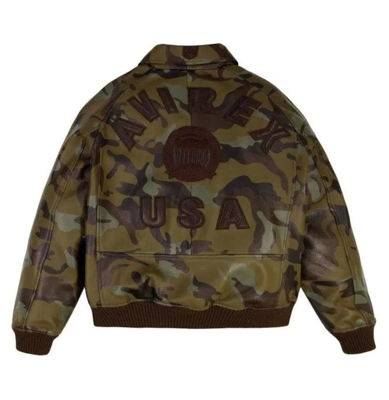 May include: Camouflage-patterned leather jacket with the word "AVIREX" arched across the back, and "USA" below. The jacket has a brown ribbed hem and cuffs. The camouflage design features shades of green, brown, and black.