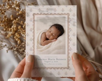 May include: A birth announcement card with a sleeping baby swaddled in a blanket. The card has a scalloped border and floral pattern. Text reads "Introducing Florence Marie Bennett, August 4, 202x, 12:48 PM, 4.08 kg, 53.34 cm."