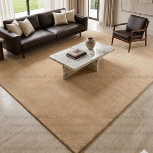 May include: A contemporary living room with a brown leather sofa, cream cushions, and a marble coffee table. A brown leather armchair sits nearby. The room is grounded by a large beige rug, creating a cohesive design.