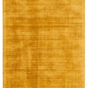 May include: A rectangular, mustard-yellow rug with a textured surface. The rug's colour is a warm, inviting shade, and the texture suggests a soft, plush feel. The rug is a solid colour, with no patterns or designs.