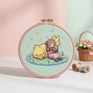 May include: A cross-stitch embroidery hoop featuring a scene with a yellow bird-like creature and a person in a pink dress. The embroidery is set against a light green background, framed by a pink hoop. A small basket of flowers and spools of thread are in the background.
