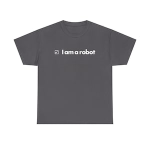 Pode incluir: T-shirt cinzenta escura com o texto branco "I am a robot" e uma marca de verificação. A t-shirt tem um design de gola redonda.