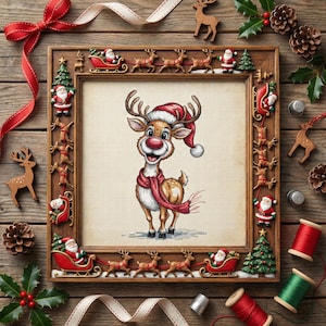 Op de afbeelding: Een kruissteek van een rendier met een kerstmuts en sjaal, omlijst met kerstversieringen. Het frame is versierd met kerstmannen, rendieren en sleeën. Rood lint, dennenappels en houten rendieren maken de feestelijke scène compleet.