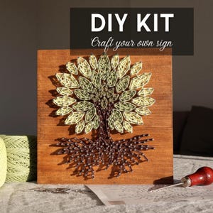May include: DIY kit to craft a tree string art sign. The wooden board features a tree design made with green and brown thread. The text "DIY KIT Craft your own sign" is at the top. Includes thread, nails, and a tool.