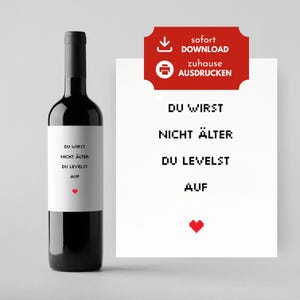 Könnte beinhalten: Eine schwarze Weinflasche mit einem weißen Etikett mit dem Text "DU WIRST NICHT ÄLTER DU LEVELST AUF" und einem roten Herzen. Ein rotes Schild mit den Worten "sofort DOWNLOAD zuhause AUSDRUCKEN" befindet sich auf der rechten Seite.