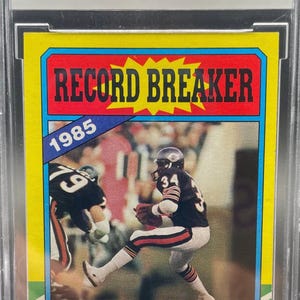 May include: A 1986 Topps Walter Payton #7 football card graded BCCG 9 Near Mint or Better. The card features a Record Breaker design with a photo of Walter Payton in a Chicago Bears uniform, text detailing his rushing record, and a yellow border.