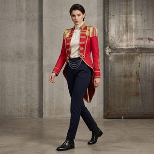 May include: A red military-style jacket with gold trim and epaulets, worn with navy blue trousers and black boots. The jacket has detailed gold embroidery and a chain. The ensemble is a fusion of traditional and modern fashion.