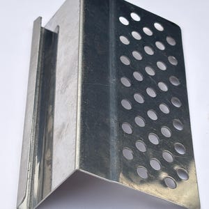 Puede incluir: Un soporte met&aacute;lico en &aacute;ngulo recto de color plateado. Un lado presenta una serie de perforaciones circulares espaciadas uniformemente. El soporte est&aacute; dise&ntilde;ado para soporte estructural.