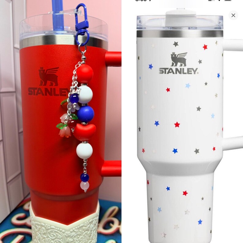 Op de afbeelding: Twee Stanley-bekers. E&eacute;n is rood met een witte basis en een kralenbedel. De andere is wit met een sterrenpatroon. Beide hebben het Stanley-logo en een handvat. De rode beker heeft een blauw rietje.