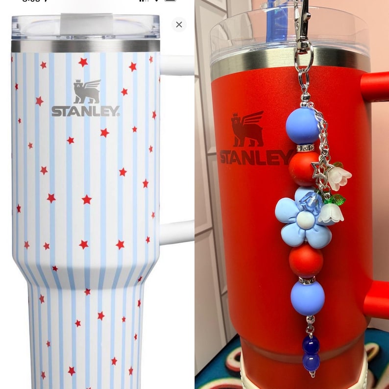 Op de afbeelding: Twee ge&iuml;soleerde Stanley-mokken. E&eacute;n is wit met blauwe strepen en rode sterren. De andere is rood met een decoratieve bedel. Beide mokken hebben het Stanley-logo en een handvat. De bedel heeft blauwe en rode kralen en bloemaccenten.