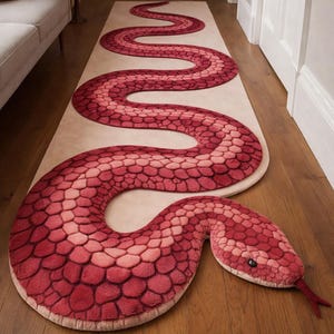 Könnte beinhalten: Ein roter und rosa schlangenförmiger Teppich mit einem strukturierten, schuppenartigen Muster. Der Teppich liegt auf einem neutralfarbenen Läufer und Parkettboden. Der Schlangenkopf hat eine rote Zunge und schwarze Augen.