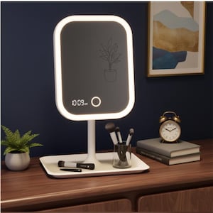 May include: A white LED vanity mirror with a rectangular shape and a built-in clock showing 10:09 AM. The mirror features a plant illustration and a touch button. It rests on a white tray with makeup brushes and a small alarm clock.