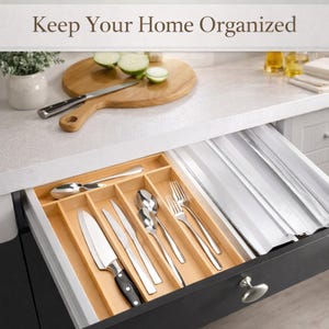 May include: A white ceramic mug with a black handle and the text "But First, Coffee" in a bold, black font. The mug is set against a blurred background, suggesting a cozy setting.