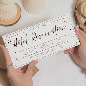 以下が含まれることがあります： 茶色の文字が入った白いホテルの予約ギフト券。「Hotel Reservation」、「A Gift Just For You」、そして「Happy Anniversary Mum & Dad! Lots of Love From Caitlin XXX」と書かれています。