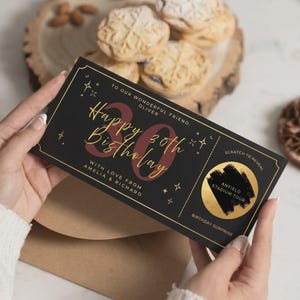 Puede incluir: Un boleto de cumpleaños rectangular negro con texto en lámina dorada que dice Happy 30th Birthday, To our wonderful friend Oliver y With love from Amelia & Richard. Incluye un círculo dorado para raspar Anfield Stadium Tour.