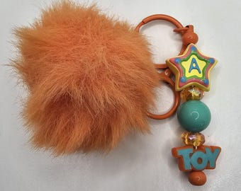 Charakter Schlüsselanhänger: mit orangem Pompom und Spielzeugmotiv