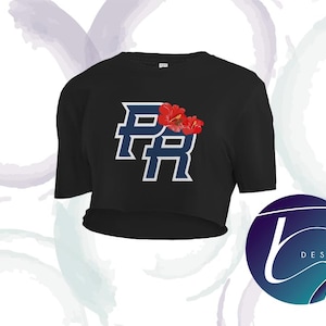 Op de afbeelding: Zwarte crop top met een wit en blauw omlijnd "PR" ontwerp en twee rode hibiscusbloemen. Het ontwerp is gecentreerd op de voorkant. Een cirkelvormig logo met het woord "DESIGN" staat in de rechter benedenhoek.