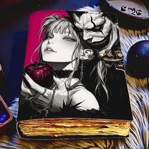 Peut inclure: Un livre à couverture rigide avec une illustration de style manga d'une femme tenant une pomme rouge, à côté d'une figure souriante. Les pages du livre sont dorées. Le fond est rose vif.