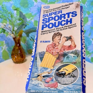 May include: Vintage Super Sports Pouch box with a blue and white design. The box features a man taking a photo, and the text "Waterproof, Shock-Resistant Carry-All for All Active Sports." The pouch measures 17 x 17 inches.