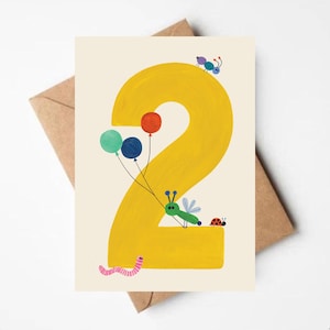 May include: A birthday card with a large yellow number 2, decorated with colourful balloons and insect illustrations. A green bug holds the balloons, with a ladybug and other insects. The card is set against a cream background.