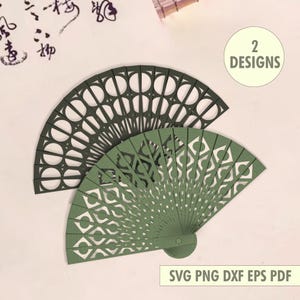 May include: Two decorative paper fans in shades of green. The top fan is a dark green, and the bottom fan is a lighter green. Both fans have intricate cut-out designs. The image includes the text "2 Designs" and "SVG PNG DXF EPS PDF".