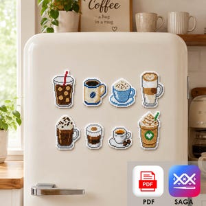 Op de afbeelding: Een set van acht kruissteekmagneten met diverse koffiedranken, waaronder ijskoffie, mokken, lattes en frappés met slagroom. Elk stuk toont een gedetailleerd rasterpatroon van geborduurde draden in tinten bruin, blauw en wit.