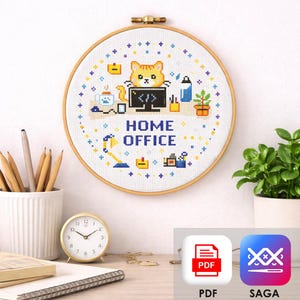 May include: A cross-stitch embroidery hoop with a cat design at a computer, the words "HOME OFFICE" are displayed. The design includes a desk lamp, coffee cup, and plant. The hoop is displayed on a white wall.