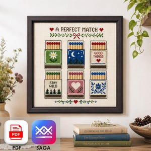 May include: A framed cross-stitch embroidery featuring the text A PERFECT MATCH and six matchboxes with various designs including a flower, a night scene, the text GOOD THINGS, the text STAY WILD, a heart, and a floral pattern on cream fabric.
