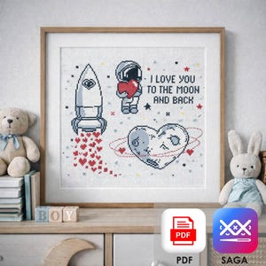 Puede incluir: Arte de punto de cruz enmarcado con un cohete, un astronauta sosteniendo un corazón y un planeta en forma de corazón. Incluye el texto "I LOVE YOU TO THE MOON AND BACK". La obra se exhibe en una estantería con juguetes.