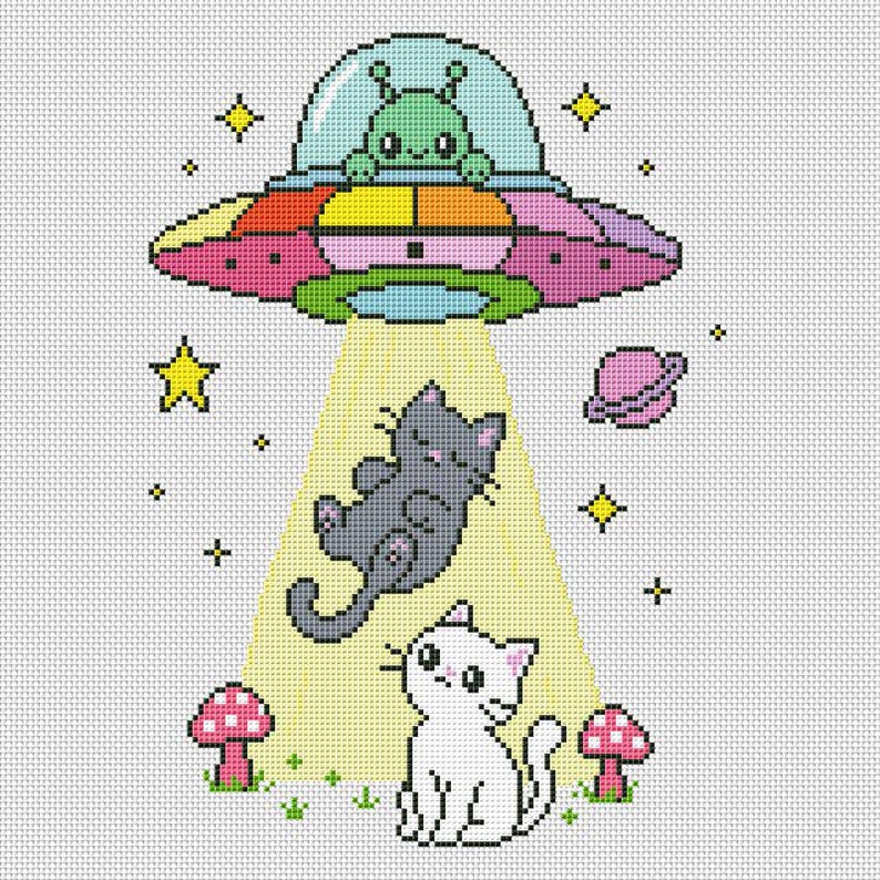 May include: A cross-stitch pattern featuring a green alien in a colorful UFO beaming up a gray cat. A white cat sits below near two pink mushrooms. The scene includes yellow stars and a small pink planet against a white grid background.