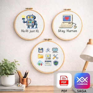 May include: Three round cross-stitch hoops with tech-themed designs. One features a robot with the text "No AI just IQ." Another shows a computer with a heart and the text "Stay Human." The third hoop displays various computer icons.
