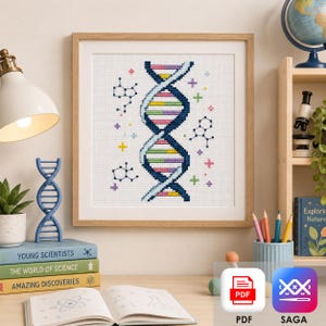 May include: Cross-stitch art of a DNA double helix in a wooden frame. The design features a blue and white background with a colorful DNA strand and molecular structures. The artwork is displayed on a desk with books and a lamp.