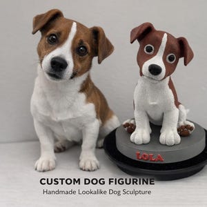 Puede incluir: Un perro Jack Russell Terrier real se sienta junto a una figura de perro hecha a medida. La figura es marrón, blanca y negra, y se asienta sobre una base gris con el nombre "LOLA" en rojo. El texto en la parte inferior dice "CUSTOM DOG FIGURINE Handmade Lookalike Dog Sculpture."