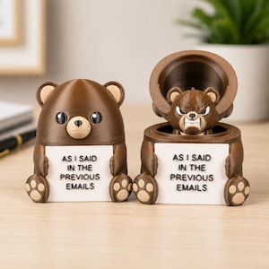 Könnte beinhalten: Zwei braune Bärenfiguren mit weißen Schildern, auf denen AS I SAID IN THE PREVIOUS EMAILS steht. Ein Bär ist geschlossen, der andere ist offen und zeigt einen kleineren, wütend aussehenden Bären im Inneren. Die Bären haben beige Ohren und Pfoten.