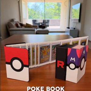 May include: A trading card binder with a red and white Pokeball design, a black binder with a red "R", and a purple and white binder with an "M". The binder is open, displaying trading cards. The text "POKE BOOK" and "Trading card binder" are visible.